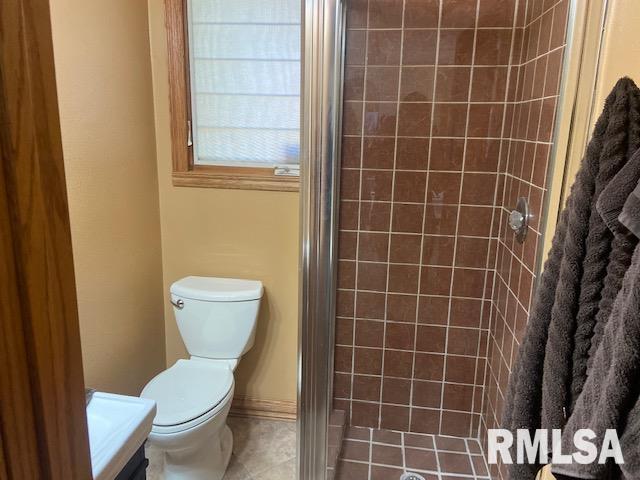 bathroom with tile patterned floors, vanity, toilet, and walk in shower