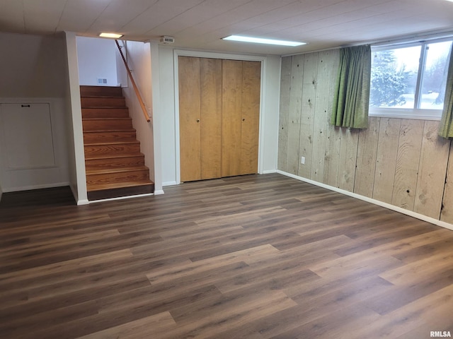 basement with wooden walls and dark wood-type flooring