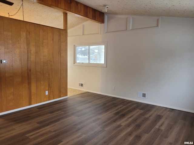 empty room with lofted ceiling with beams, dark wood-type flooring, and wood walls