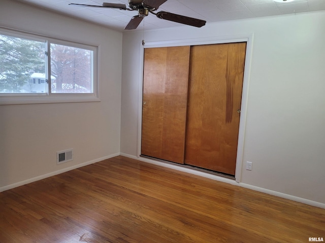 unfurnished bedroom with hardwood / wood-style flooring, ceiling fan, and a closet