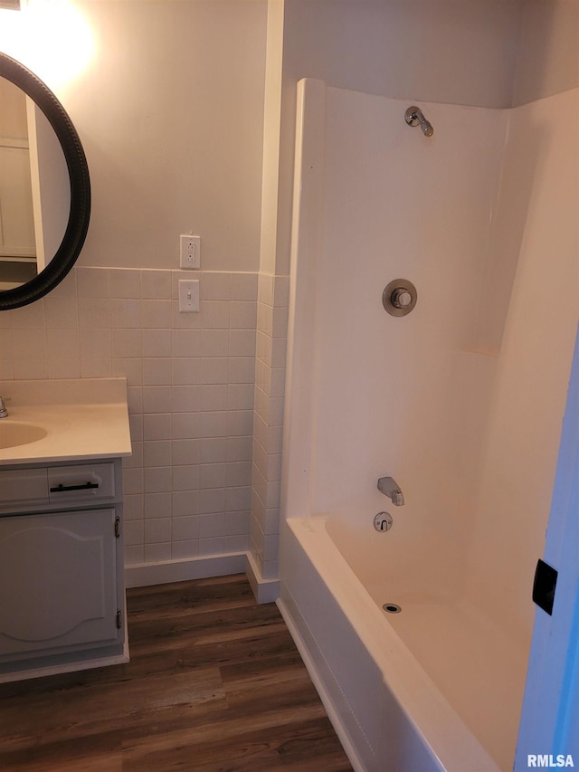 bathroom featuring hardwood / wood-style floors, vanity, shower / washtub combination, and tile walls