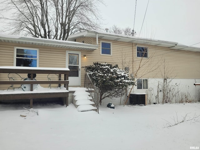 snow covered rear of property featuring central air condition unit and a deck