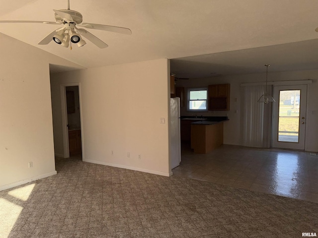 unfurnished living room featuring dark carpet, ceiling fan, lofted ceiling, and sink