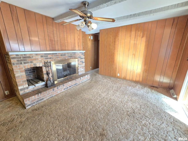 unfurnished living room featuring carpet flooring, a brick fireplace, ceiling fan, and beamed ceiling