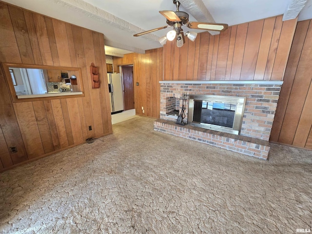 unfurnished living room featuring a brick fireplace, ceiling fan, and wood walls