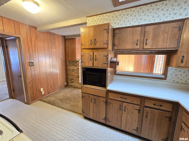 kitchen with black microwave, light carpet, and wood walls