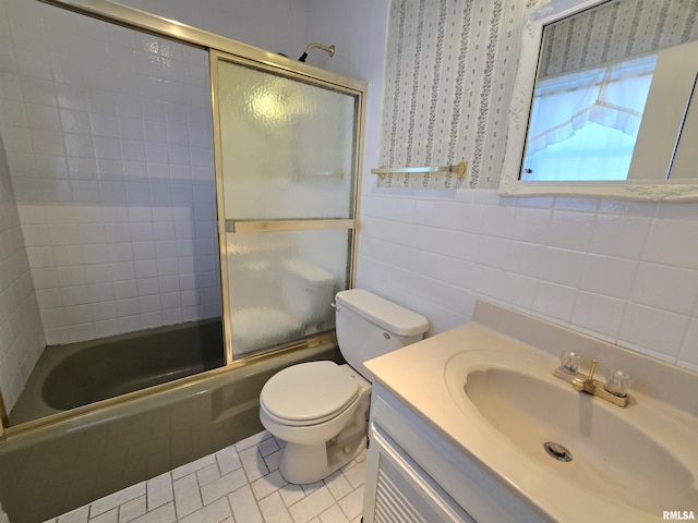 full bathroom featuring vanity, tile patterned floors, combined bath / shower with glass door, toilet, and tile walls