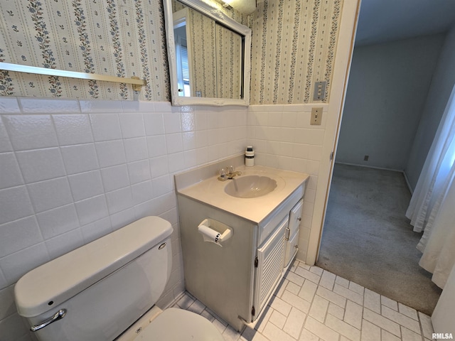 bathroom with vanity, toilet, and tile walls