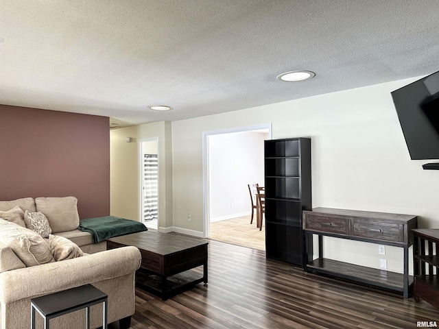 living room featuring dark wood-type flooring and a textured ceiling