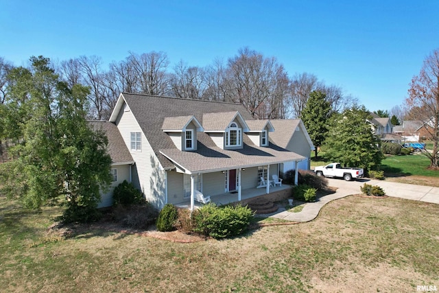 view of side of property with a lawn, covered porch, concrete driveway, and a shingled roof