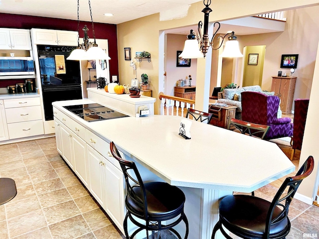 kitchen with black appliances, an inviting chandelier, white cabinets, a center island, and hanging light fixtures