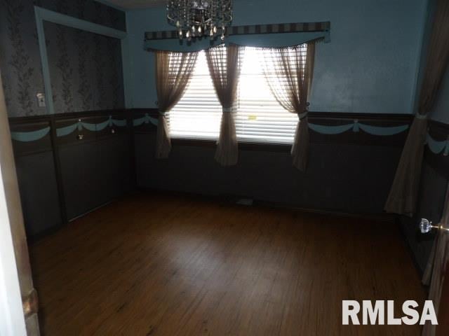 unfurnished dining area with wood finished floors and a notable chandelier