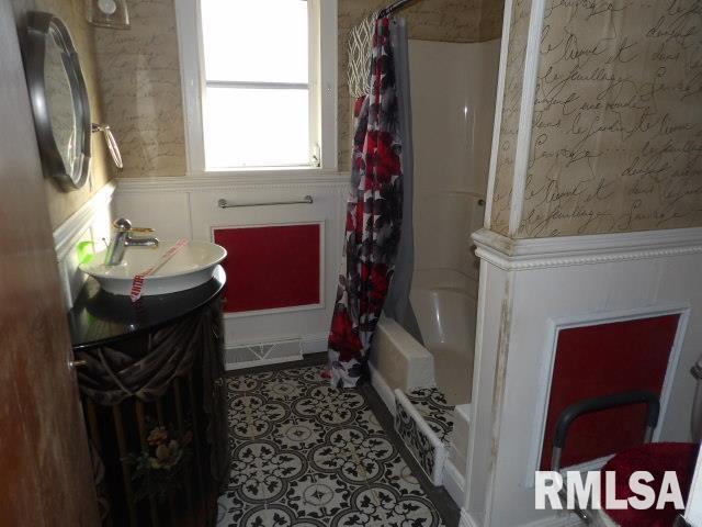 bathroom with shower / tub combo, visible vents, wainscoting, tile patterned floors, and wallpapered walls