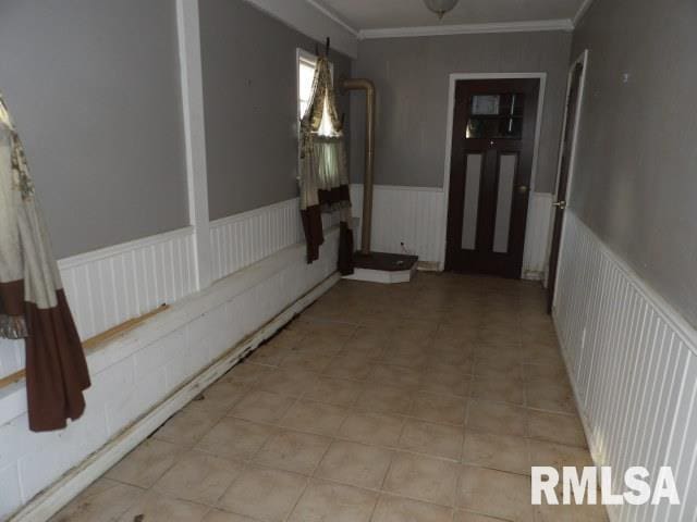 corridor featuring a wainscoted wall and ornamental molding