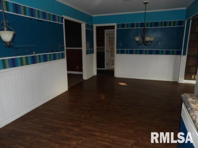 unfurnished room with a chandelier, wainscoting, wood finished floors, and crown molding