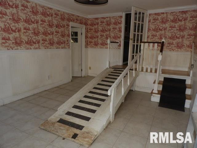 staircase with tile patterned floors, a wainscoted wall, and wallpapered walls