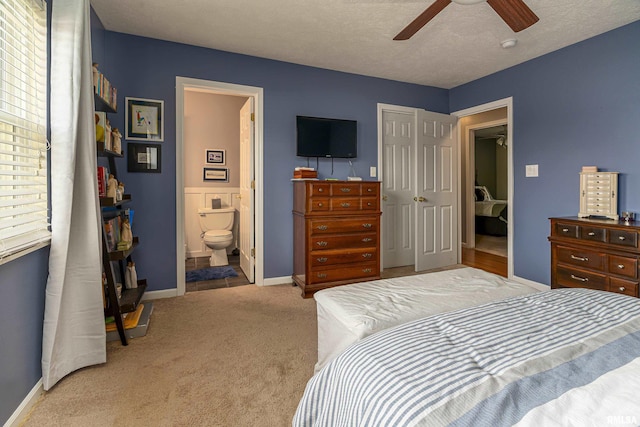 bedroom featuring ensuite bath, ceiling fan, light colored carpet, a textured ceiling, and a closet