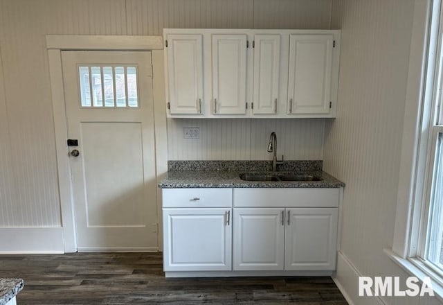 kitchen featuring dark hardwood / wood-style floors, white cabinetry, sink, and dark stone counters