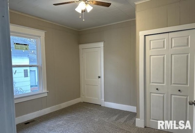 unfurnished bedroom featuring carpet flooring, a closet, ceiling fan, and crown molding