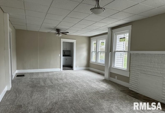 empty room with carpet floors, a drop ceiling, and ceiling fan