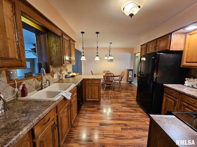 kitchen with sink, dark wood-type flooring, backsplash, decorative light fixtures, and black appliances