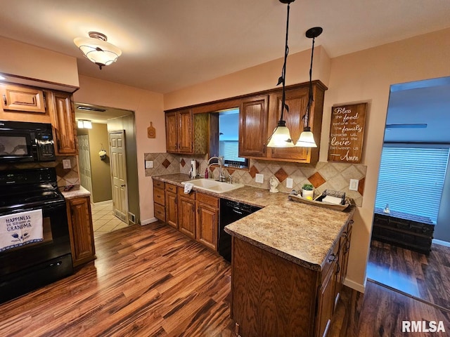 kitchen featuring tasteful backsplash, sink, black appliances, and decorative light fixtures