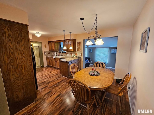 dining area featuring dark hardwood / wood-style flooring, a notable chandelier, and sink