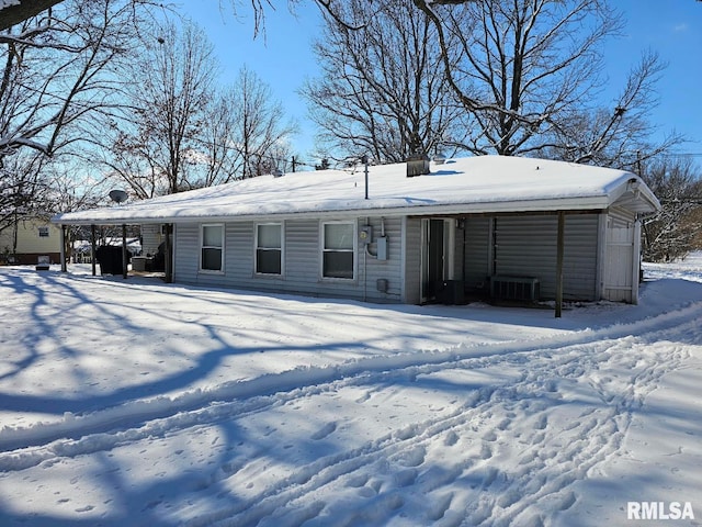 snow covered rear of property featuring central air condition unit