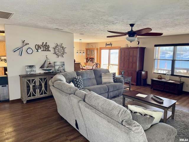 living room featuring a textured ceiling, dark hardwood / wood-style flooring, and ceiling fan