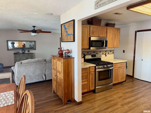 kitchen with decorative backsplash, dark hardwood / wood-style flooring, a textured ceiling, stainless steel appliances, and ceiling fan