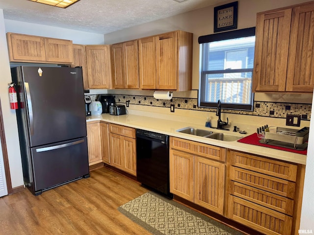 kitchen with a textured ceiling, sink, light hardwood / wood-style flooring, dishwasher, and stainless steel refrigerator