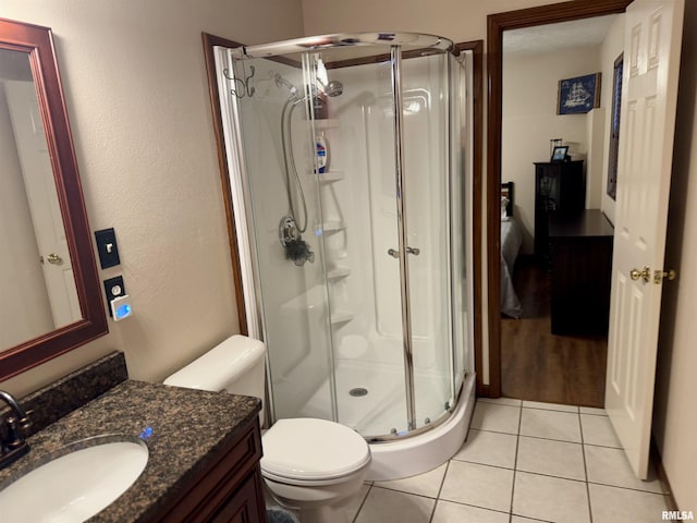 bathroom featuring tile patterned flooring, vanity, toilet, and a shower with shower door