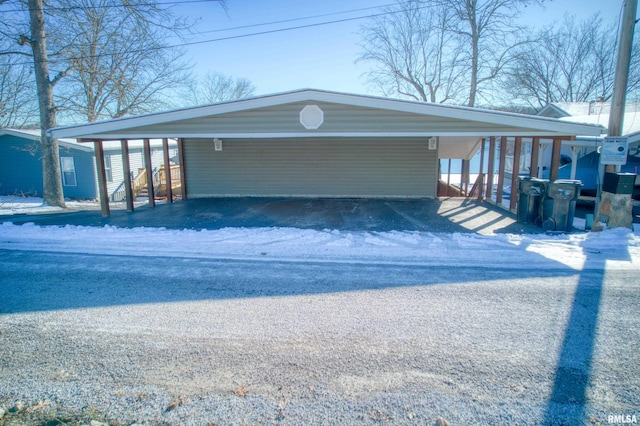 snow covered garage featuring a carport