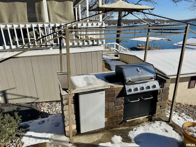 snow covered patio featuring a wooden deck, exterior kitchen, and a grill