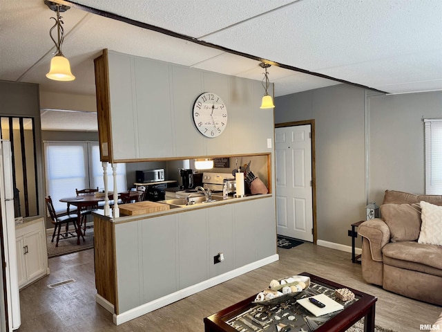 kitchen featuring dark wood-style flooring, a sink, visible vents, open floor plan, and hanging light fixtures