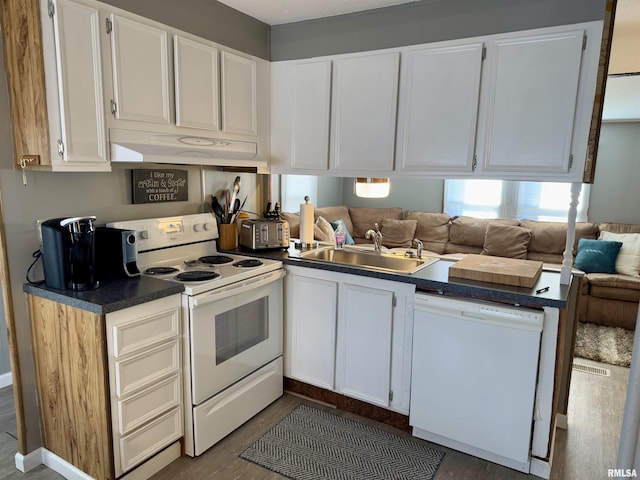 kitchen featuring dark countertops, white cabinets, a sink, white appliances, and under cabinet range hood