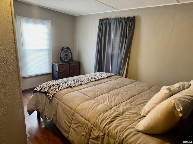 bedroom with a textured wall and wood finished floors