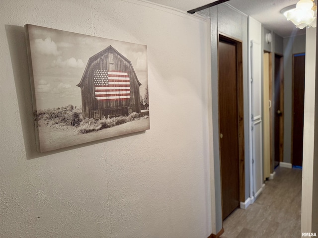 hallway featuring wood finished floors and a textured wall