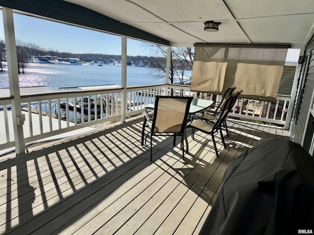 wooden terrace featuring outdoor dining area and a water view