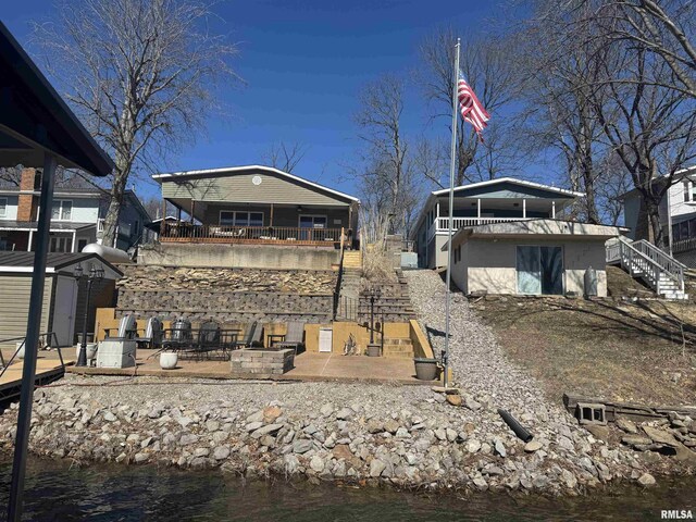 back of house with stairs, a patio area, a fire pit, and a water view