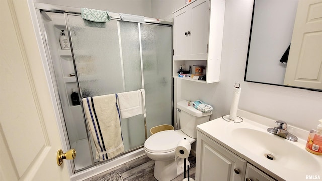 bathroom featuring vanity, hardwood / wood-style flooring, toilet, and a shower with shower door