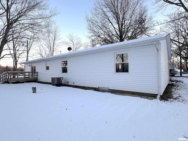 snow covered property featuring a deck and central AC