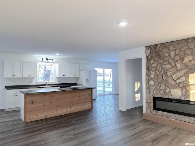 kitchen with a fireplace, sink, white cabinets, a center island, and white fridge with ice dispenser