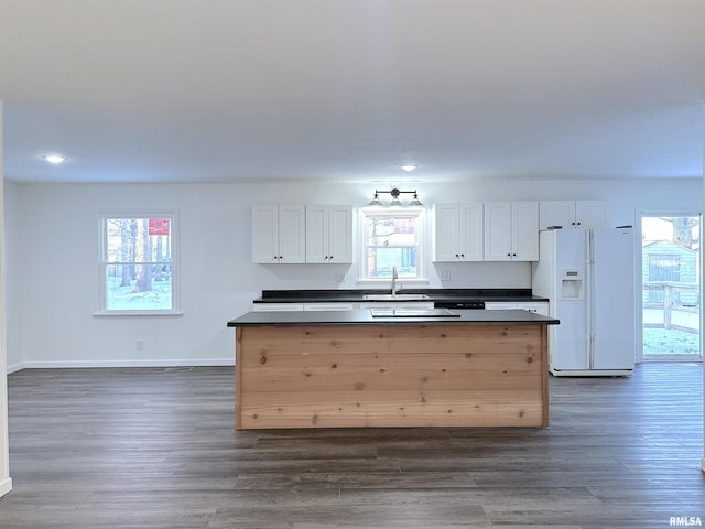 kitchen with white cabinetry, white fridge with ice dispenser, dark hardwood / wood-style floors, and sink