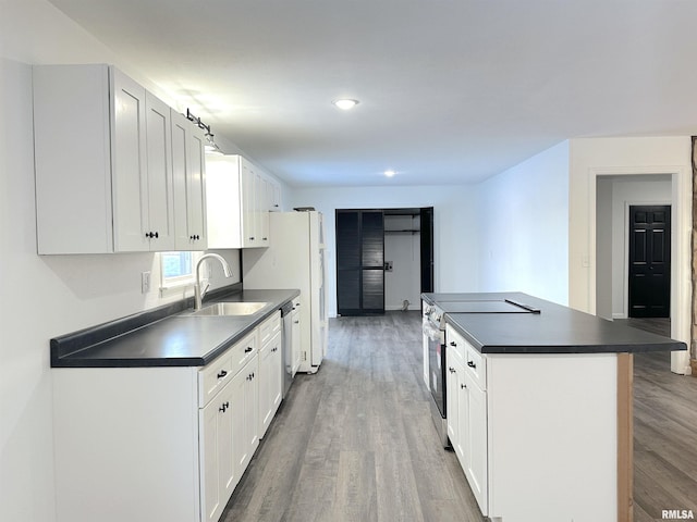 kitchen with appliances with stainless steel finishes, a kitchen island, sink, dark hardwood / wood-style floors, and white cabinetry