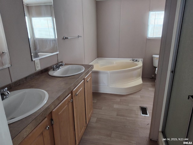 bathroom with hardwood / wood-style flooring, plenty of natural light, toilet, and a tub