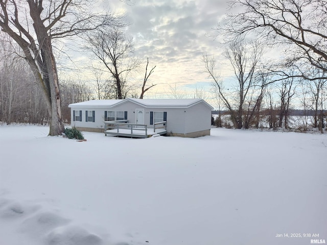 snow covered rear of property with a deck