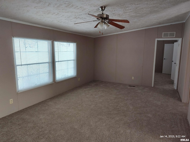 carpeted empty room with a wealth of natural light, ceiling fan, crown molding, and a textured ceiling