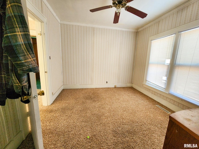 unfurnished room with carpet, a wealth of natural light, crown molding, and ceiling fan