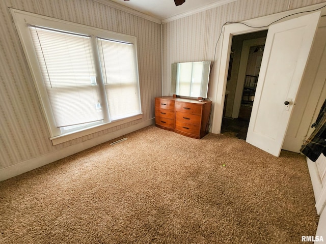 unfurnished bedroom featuring ceiling fan, carpet, and ornamental molding